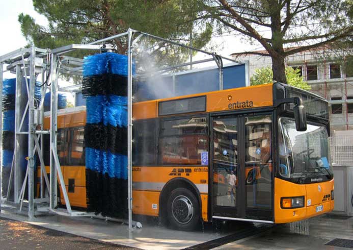 A large public transit bus going through a bus wash system.