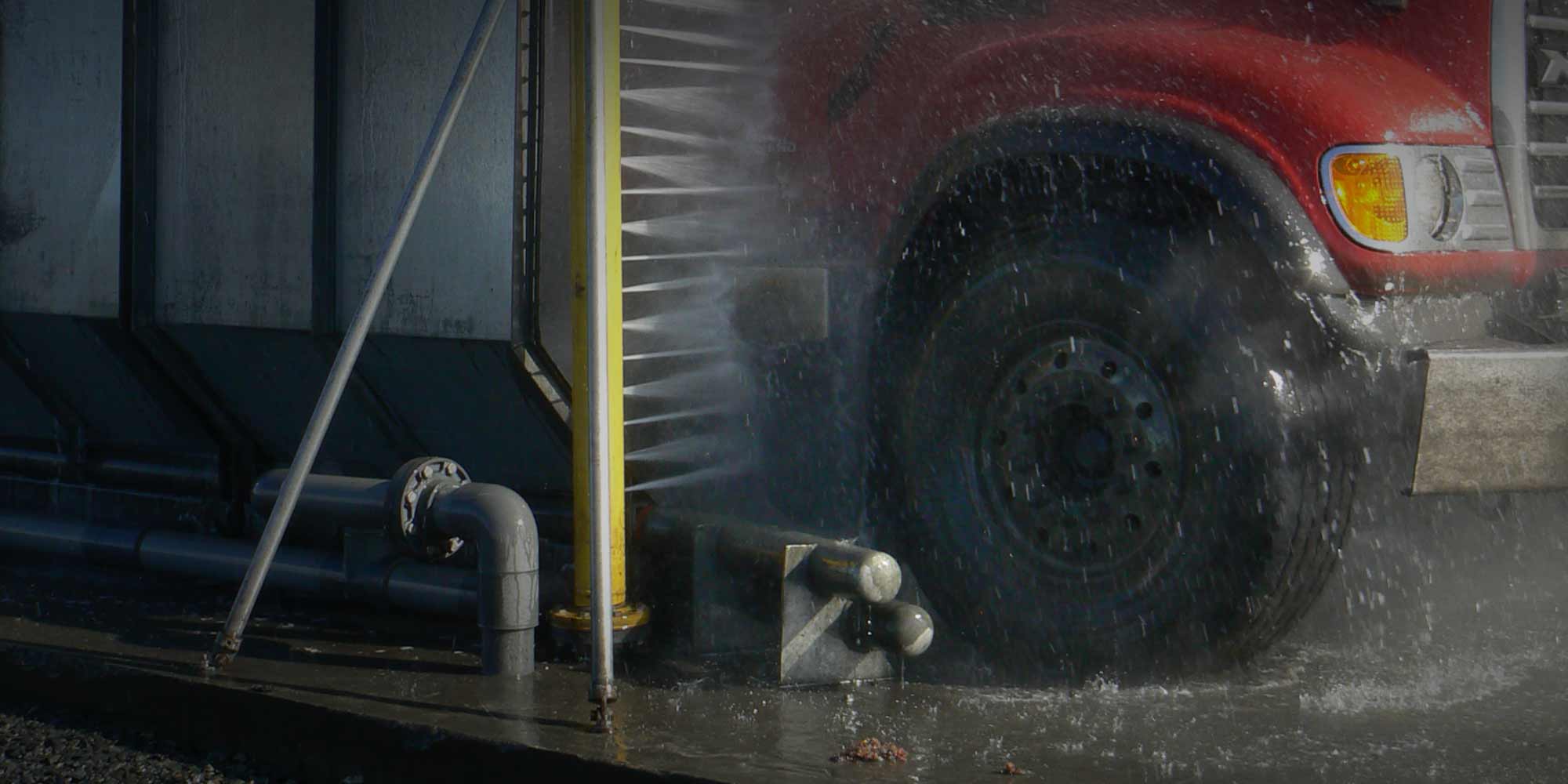 A tire wash system splashing a semi truck tire.