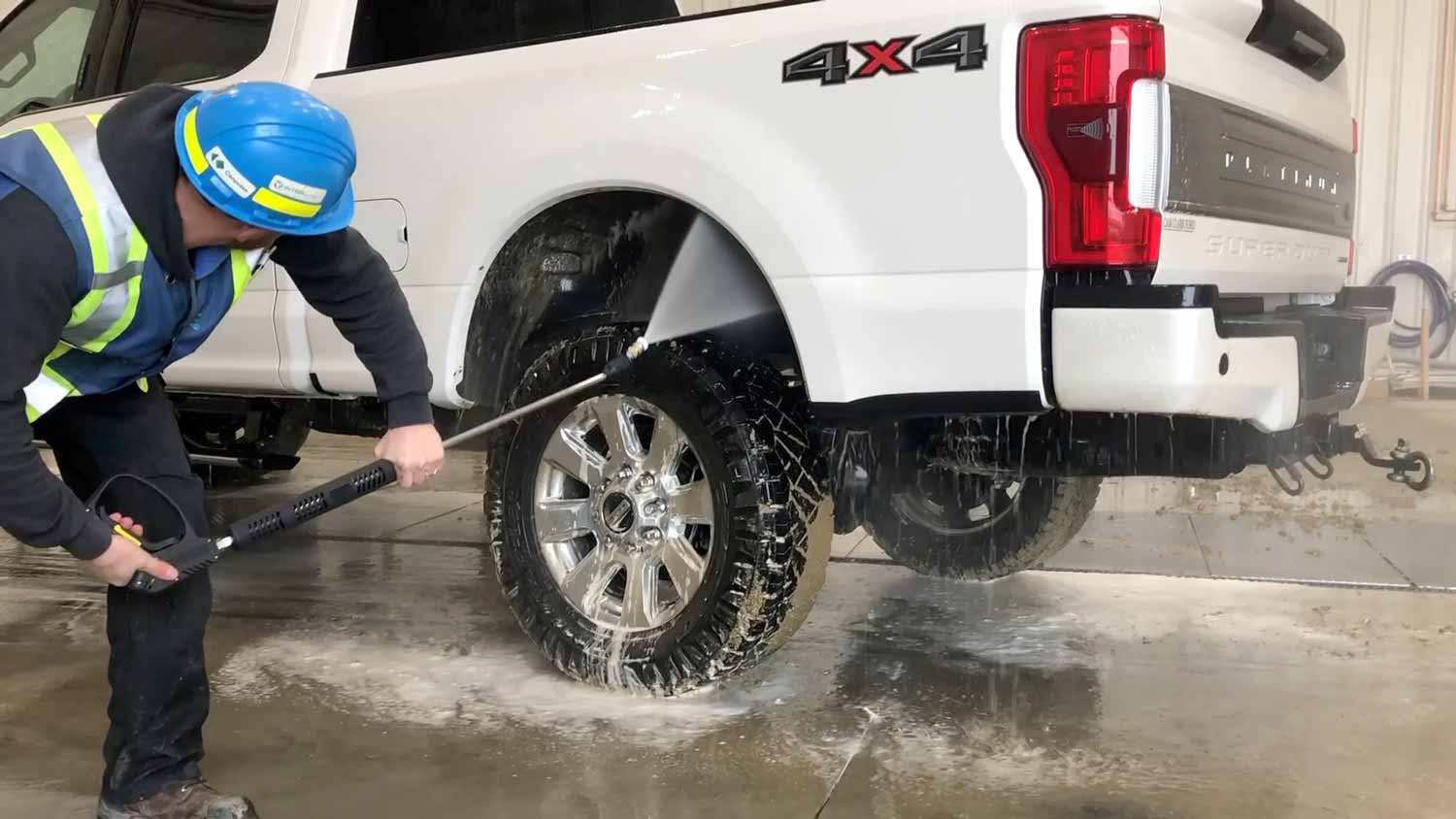 Pressure washing a truck's wheel well.