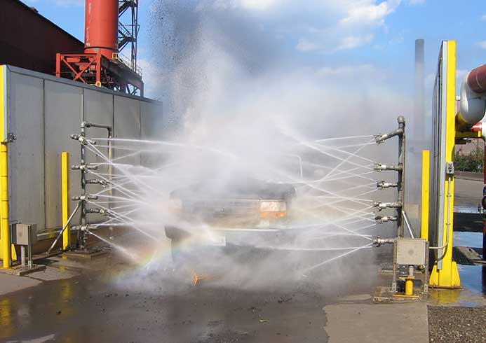 A semi-truck being sprayed down in a vehicle wash system.