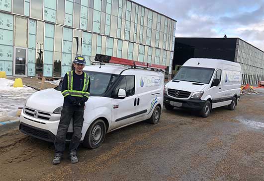 Two NoviClean technician standing in front of two wash equipment service vehicles.