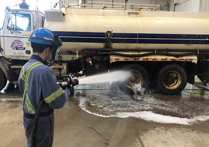 A person spraying a construction vehicle with water.